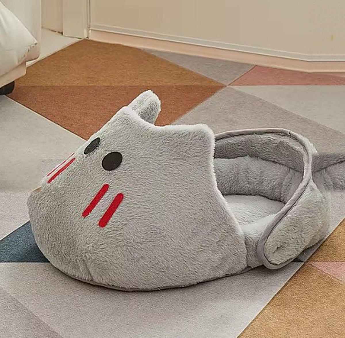 Grey SnoozeSlipper cat bed on a living room floor, hood raised